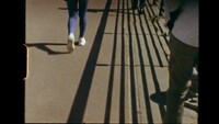 Depicts the legs of a runner wearing purple tights and white sneakers, as well as the legs of two other pedestrians. Prominent in the image is the shadow of a railing casted on the surface of the road.