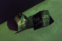 Two black event flyers laying crumpled on a floor featuring white text which reads 