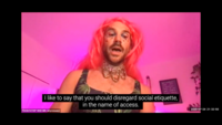 DJ Who Girl appears in a soft pink-lit room. They wear a hot pink wig, a collar with hanging chains, and a dress with visible leaves on it. Their face is adorned and their mouth open to speak. The captioning at the bottom of the screen reads, “I like to say that you should disregard social etiquette, in the name of access.” The timestamp reveals that this screen shot was taken on July 24, 2020.